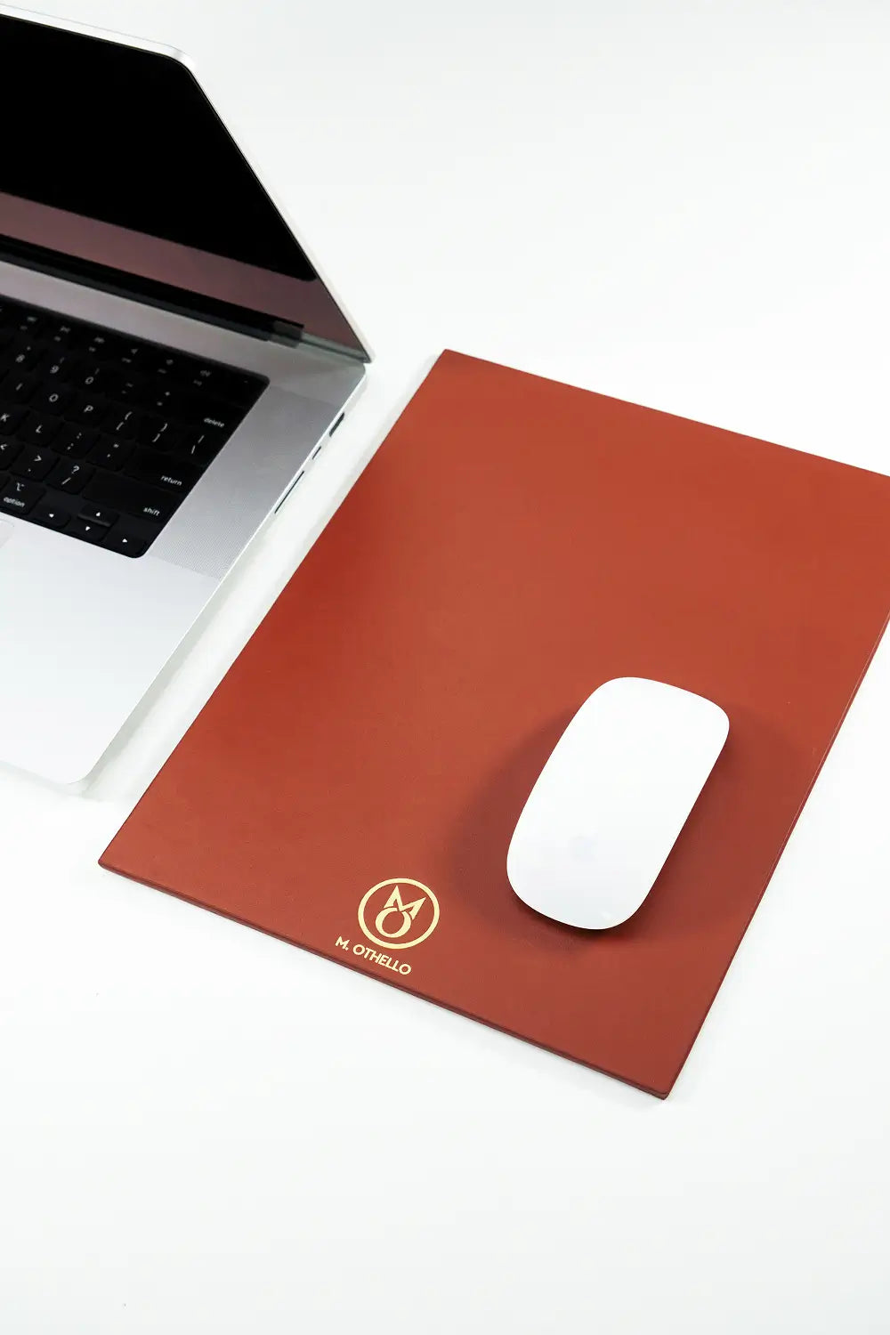 Brown leather mousepad with 'M. Othello' logo on a light background