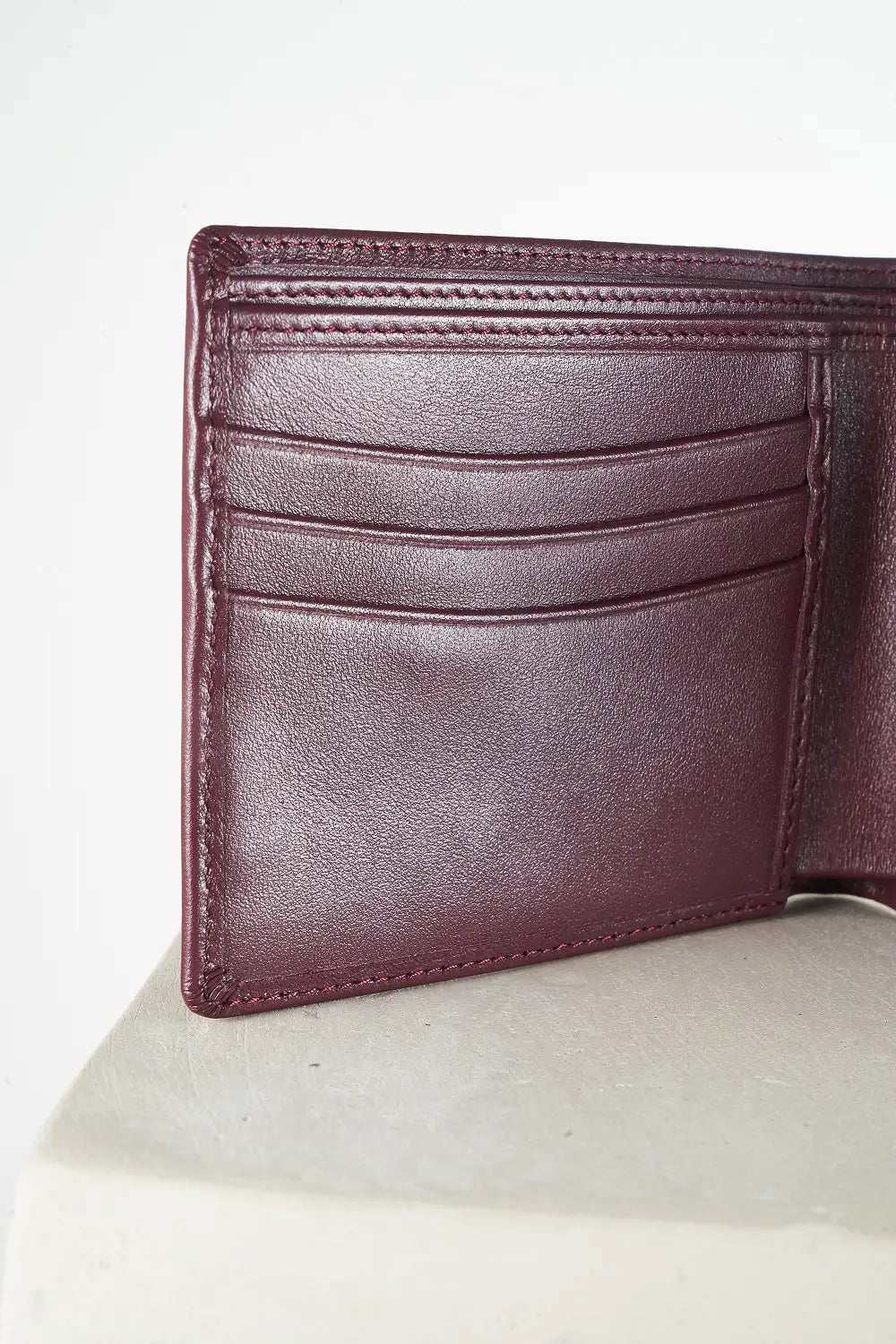 Burgundy bi-fold wallet with brand logo on a light background