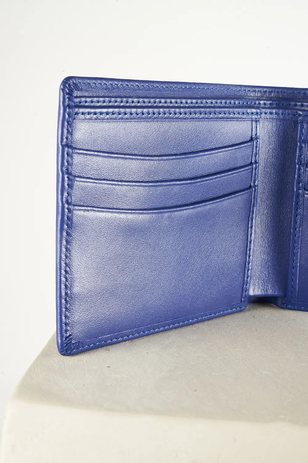 Blue bi-fold wallet with brand logo on a light background