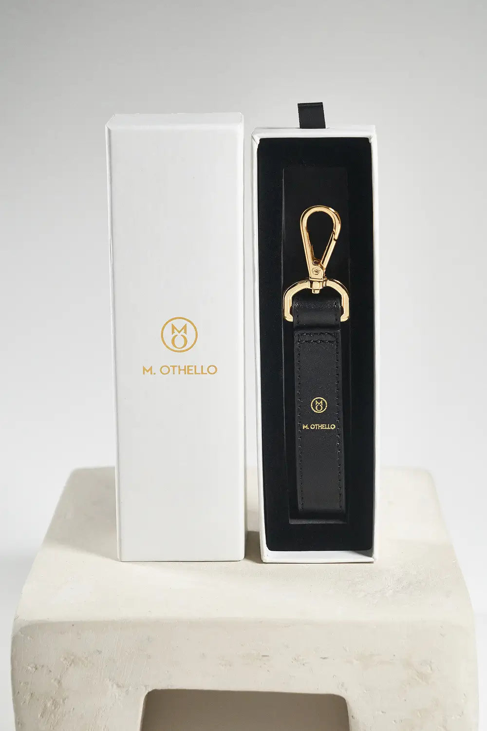 Black leather keychain with gold clasp on a white background