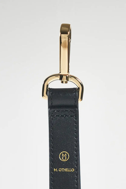 Black leather keychain with gold clasp on a white background