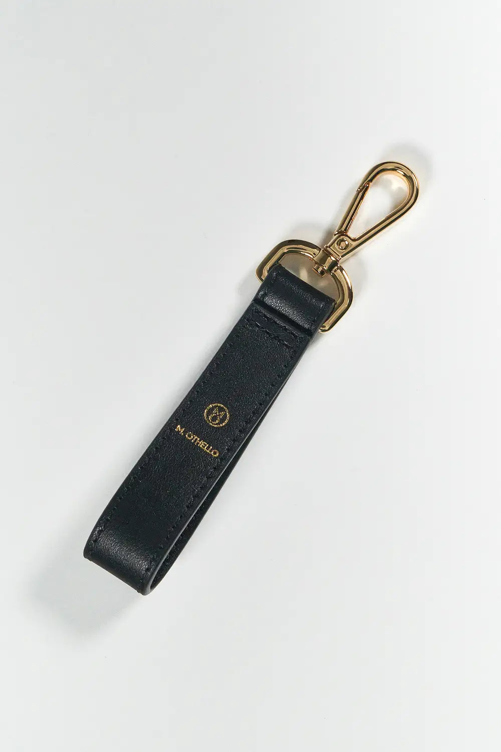 Black leather keychain with gold clasp on a white background
