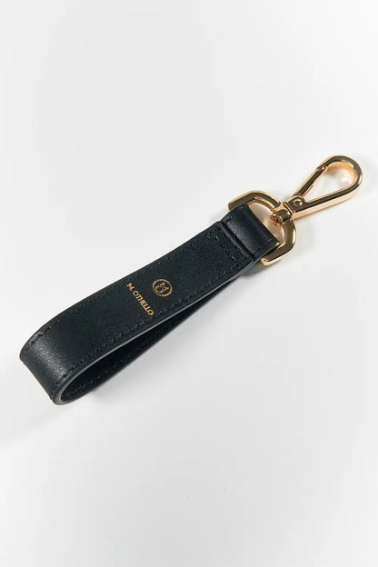 Black leather keychain with gold clasp on a white background