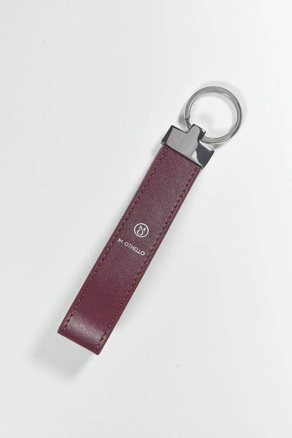 Burgundy keychain with silver ring on a light gray background