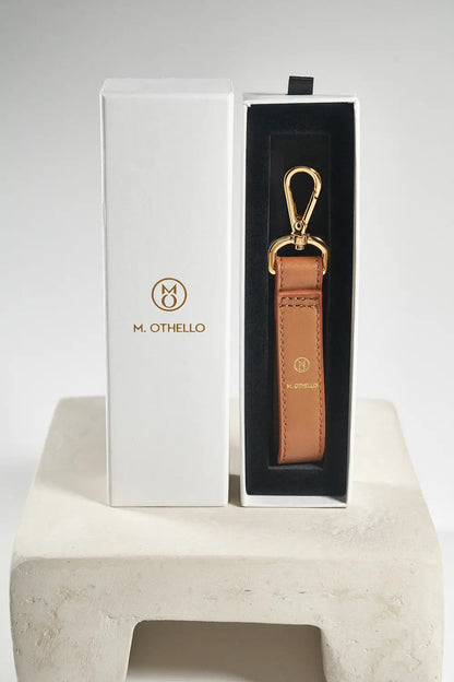 Brown leather keychain with gold clasp on a white background