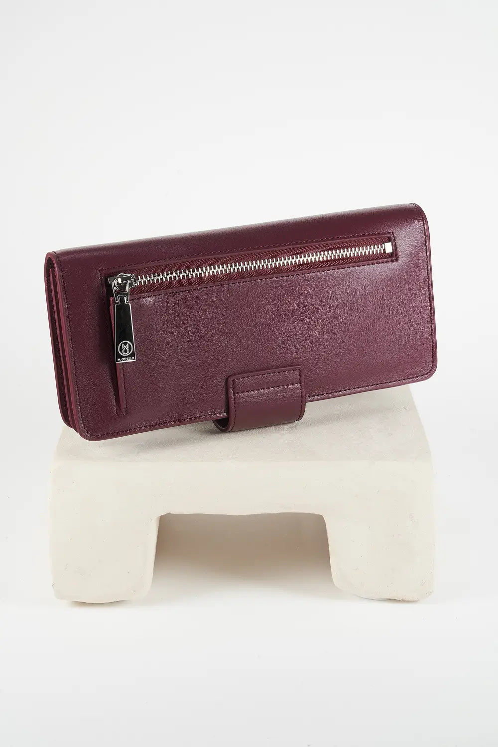 Burgundy leather wallet with 'M. Othello' branding on a light gray background.