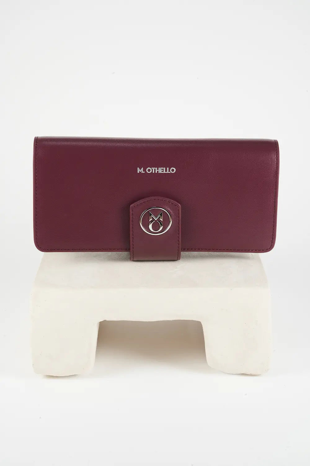 Burgundy leather phone wallet with 'M. Othello' branding on a light gray background.