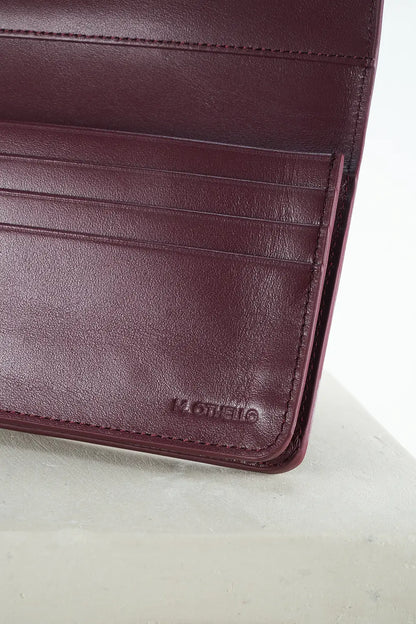Close-up of a burgundy leather wallet with 'M. Othello' branding on a light gray background.