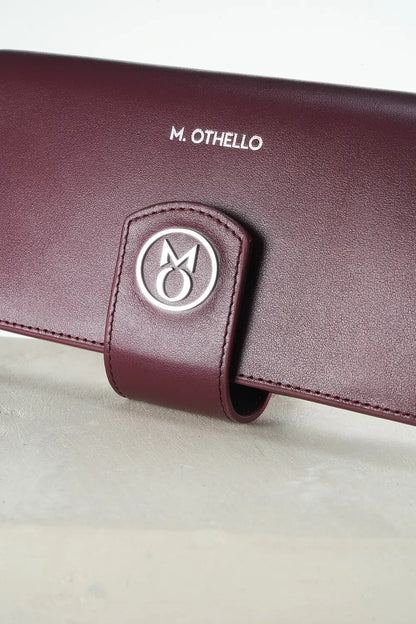 Burgundy leather wallet with 'M. Othello' branding on a light gray background.