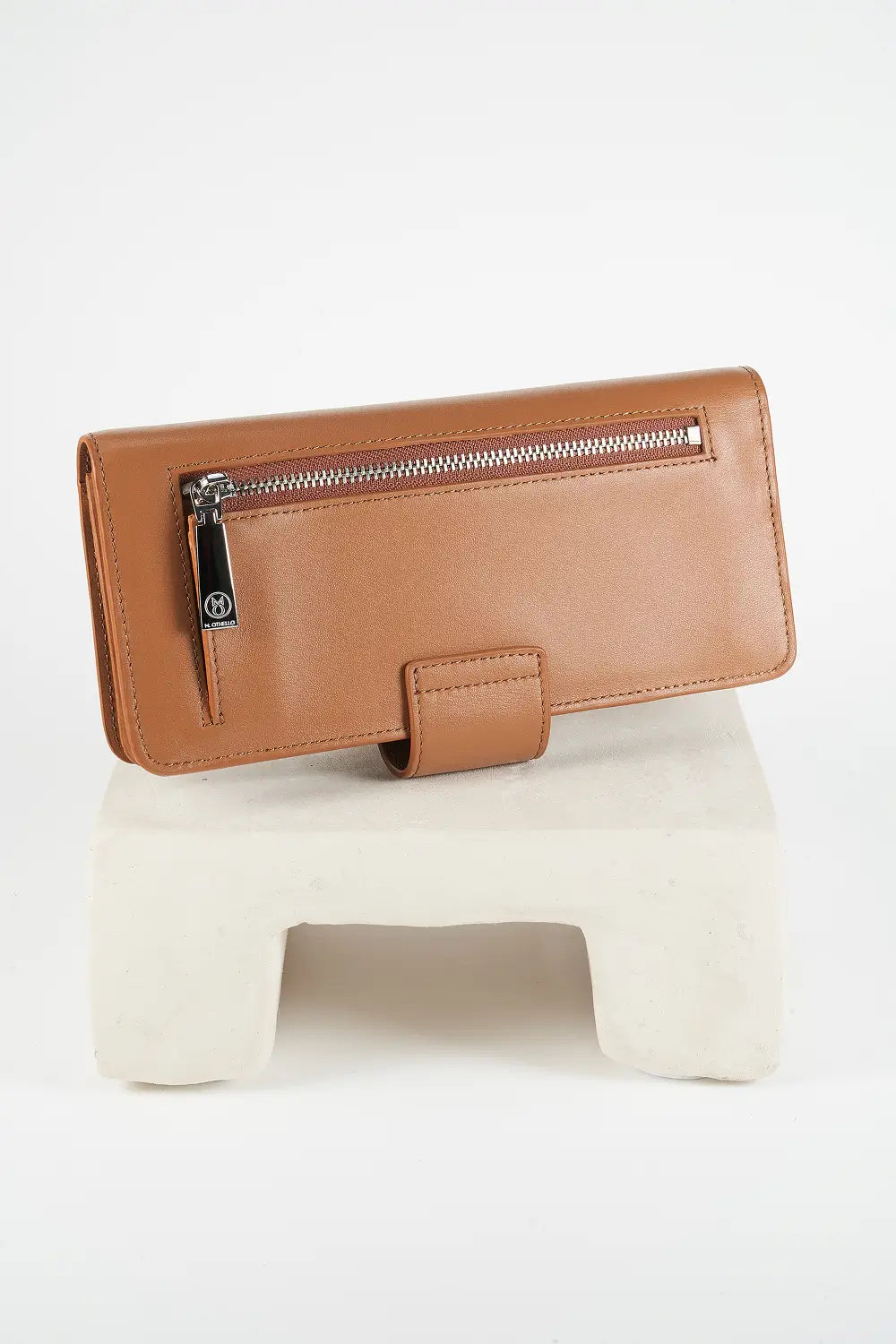 Brown wallet with a zipper on a white stand against a white background