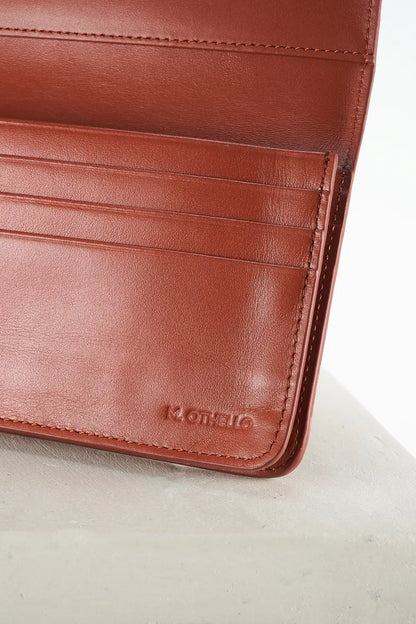 Close-up of a brown leather wallet with 'M.Othello' branding on a light background