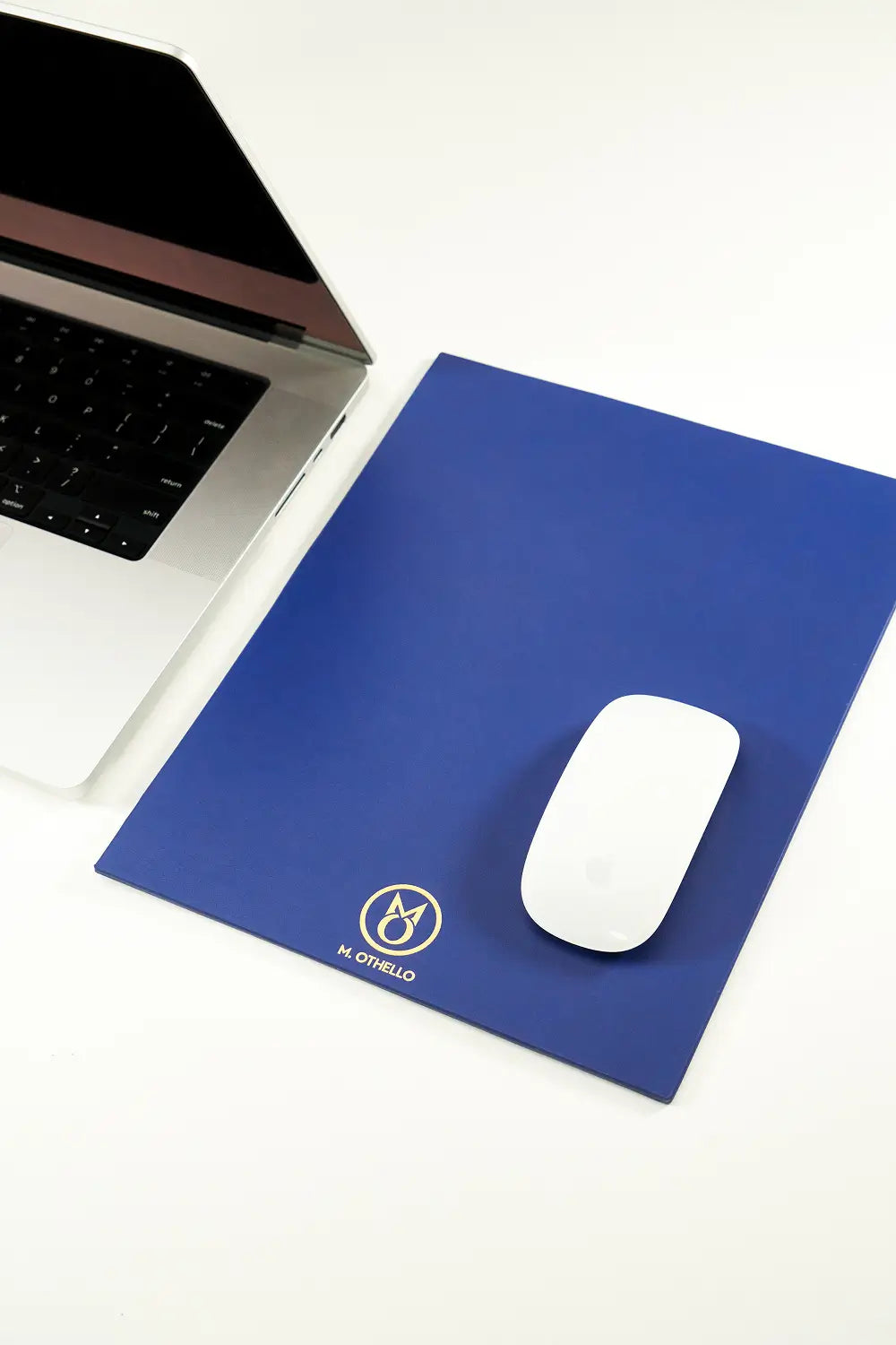 Blue leather mousepad with 'M. Othello' logo on a light background
