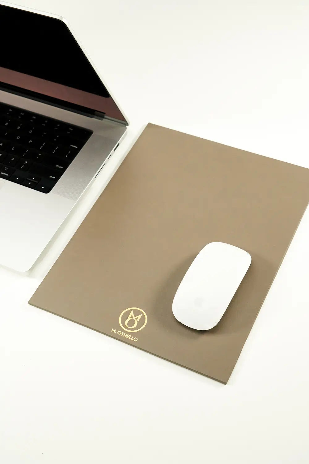 Gray leather mousepad with 'M. Othello' logo on a light background